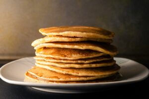 Stack of golden protein pancakes drizzled with syrup for Pancake Day 2026